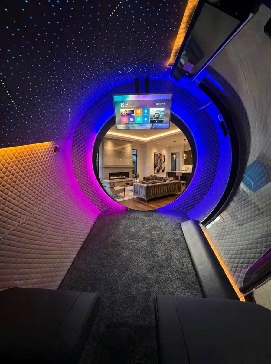 Interior of the OxyVista chamber with a fiber-optic starlight ceiling, purple and blue LED accent lighting, mounted touchscreen, diamond-quilted walls, and a round porthole framing a luxury living room